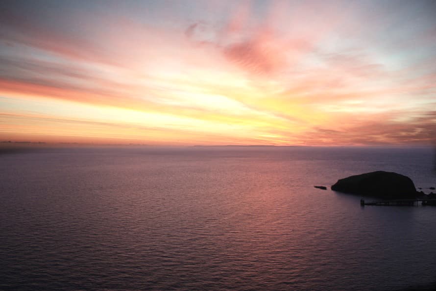 A calm sea at sunset under a pastel sky