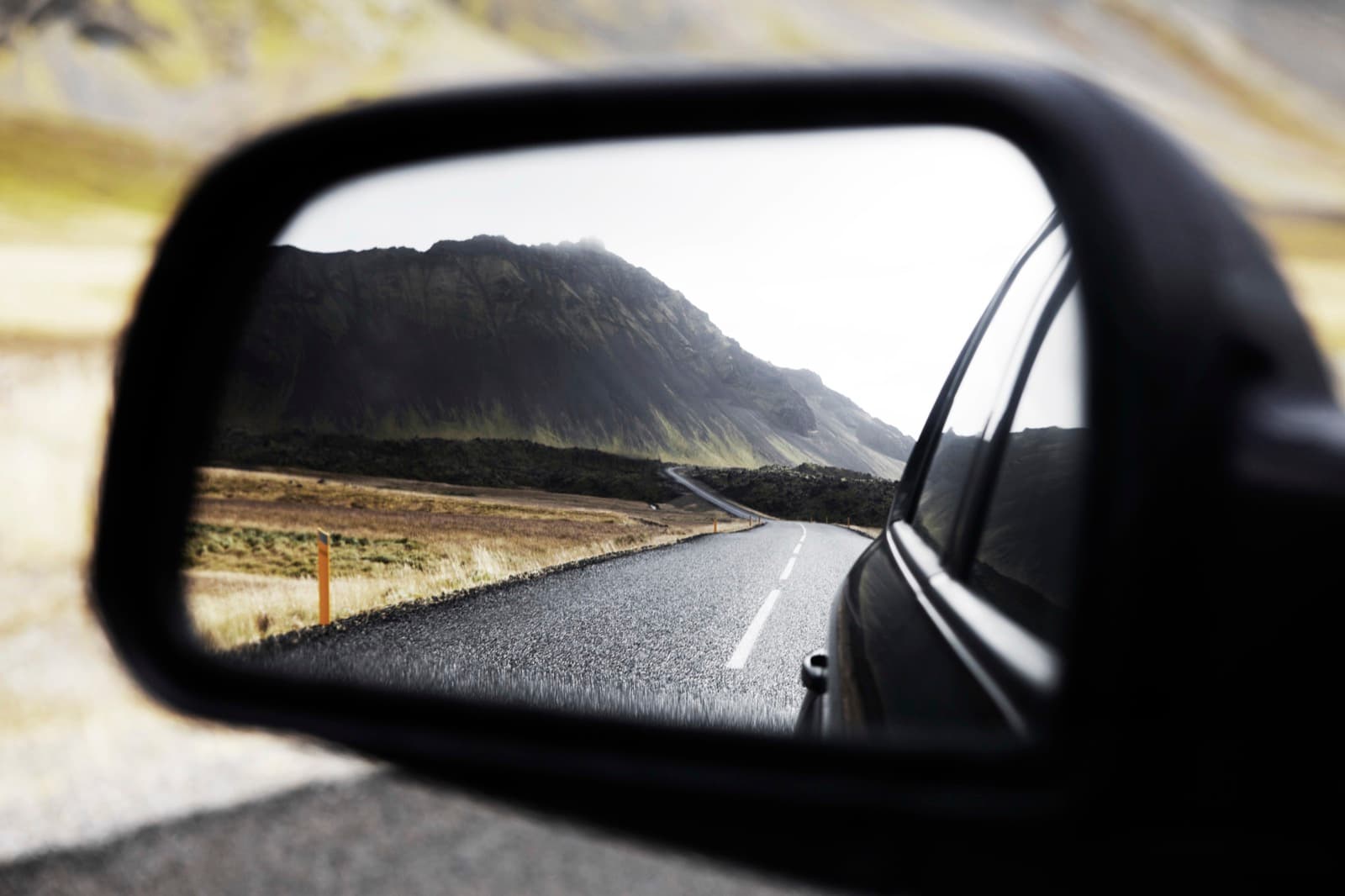 A mountain road seen in a car wing mirror