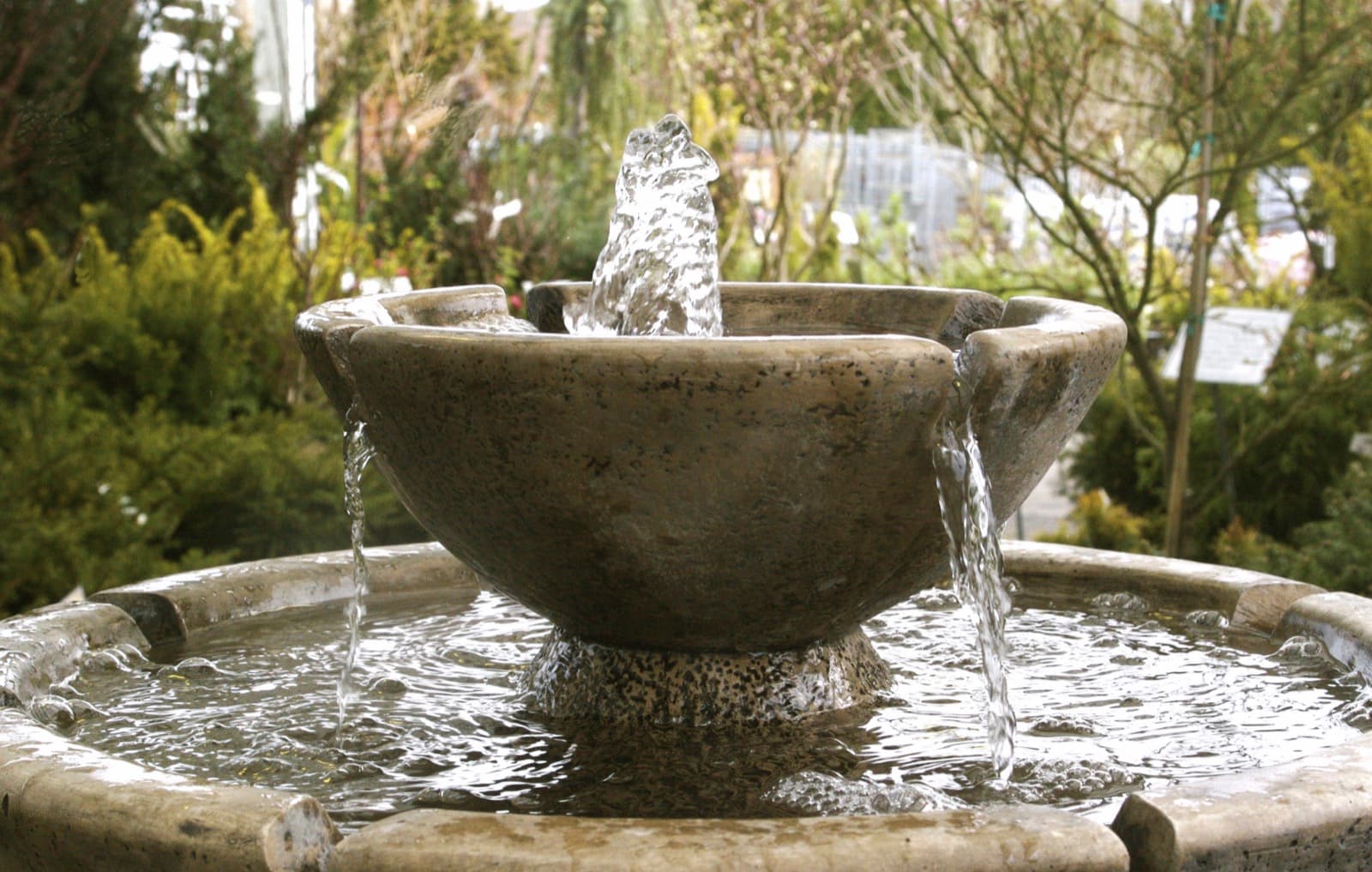Water overflowing from a stone fountain bowl in a garden