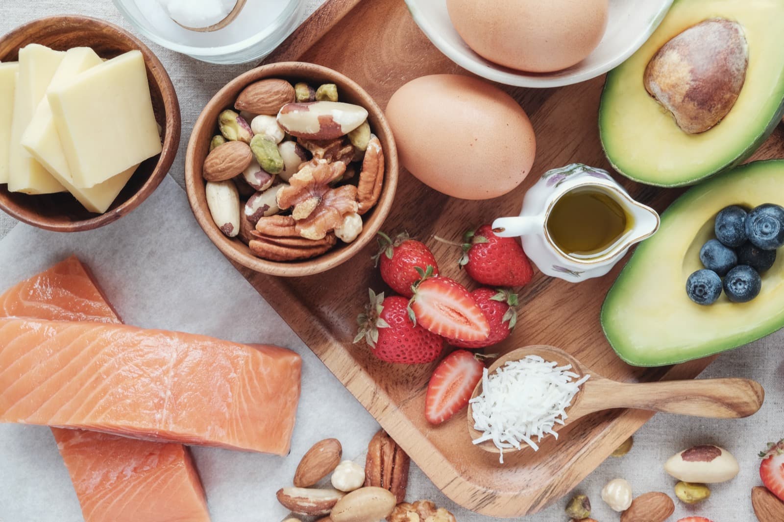 A board of whole foods: salmon, nuts, eggs, avocado, berries and olive oil