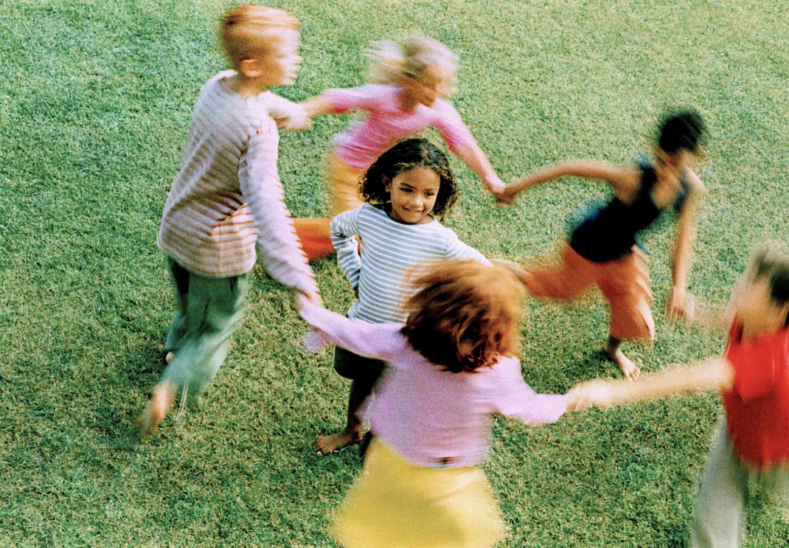 Children holding hands and playing in a ring on the grass