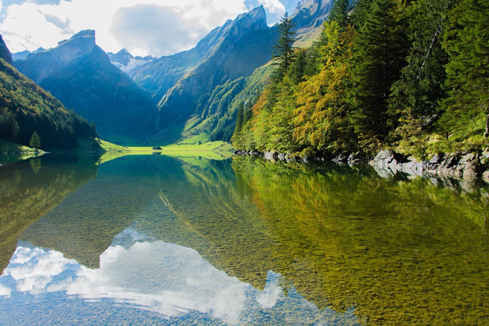 A still mountain lake reflecting forested peaks