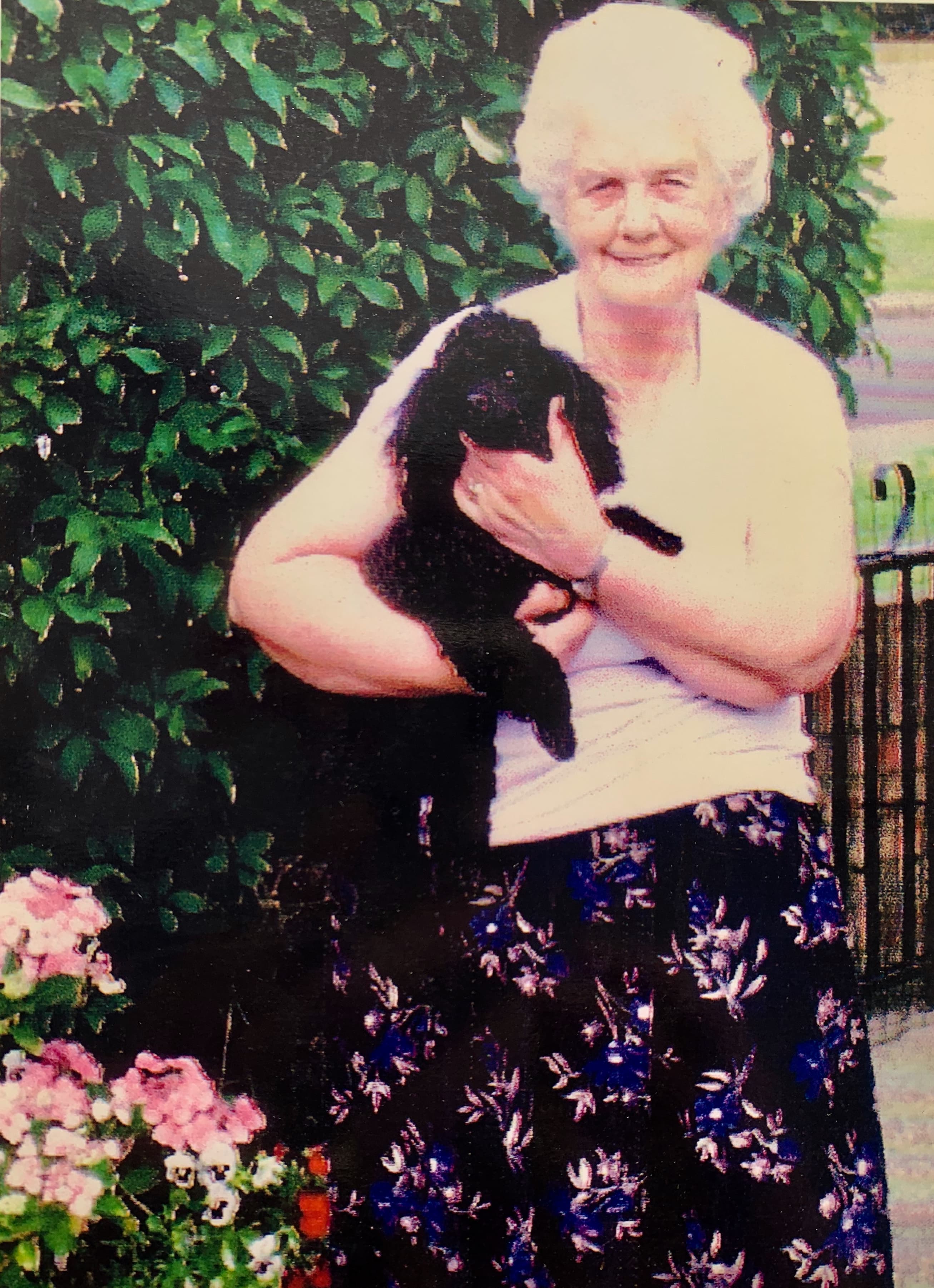 Gayle's Nan, Hilda, smiling in her garden holding a black cat